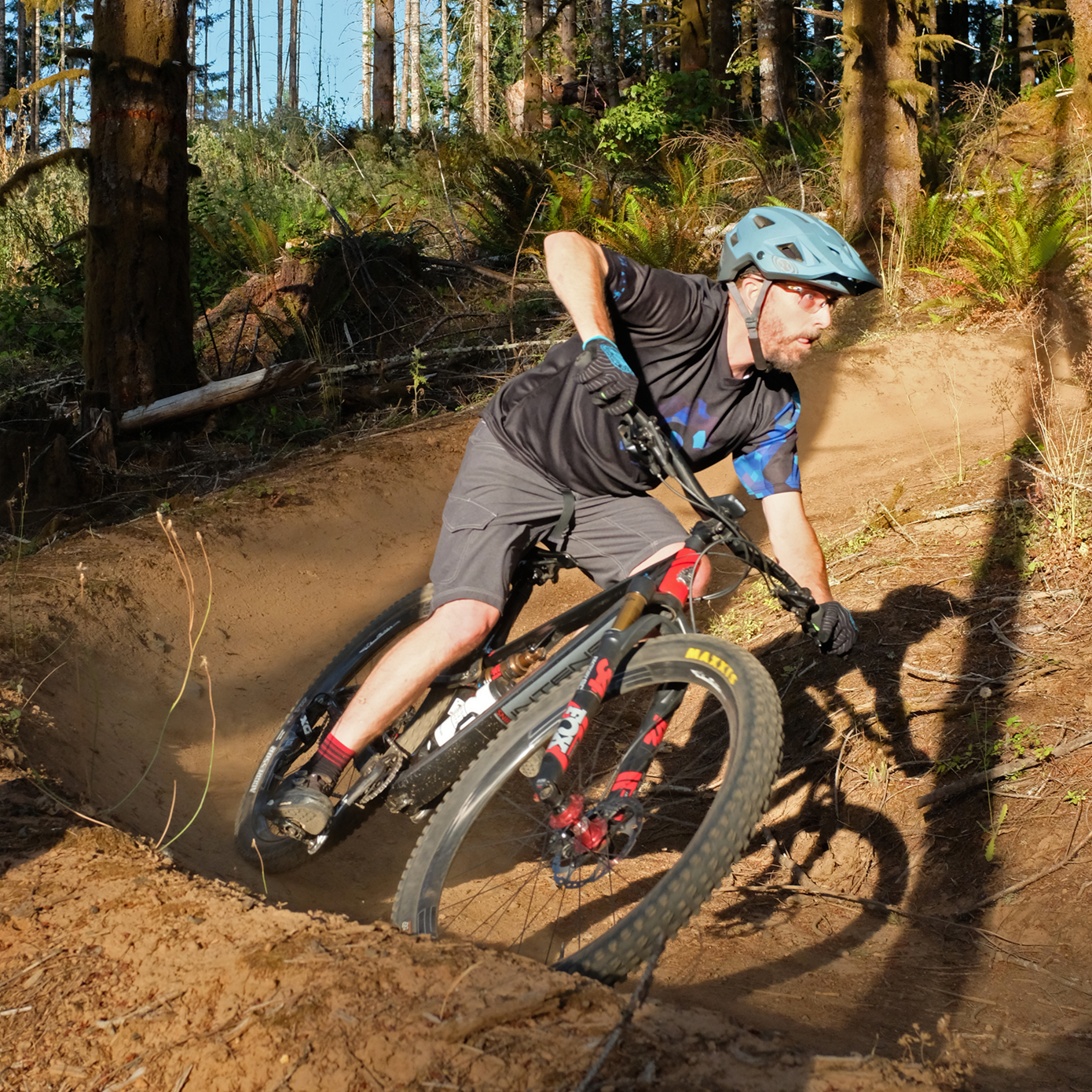 A male mountain biker, shredding a gnarly berm.